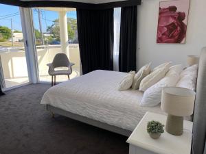 a bedroom with a white bed and a large window at Seashells Apartment 9, 21-23 Magnus Street in Nelson Bay