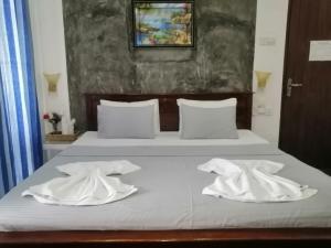 a bed with two white towels on top of it at Le Petit Hotel & Restaurant in Negombo