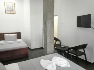 a hotel room with two beds and a tv at Le Petit Hotel & Restaurant in Negombo
