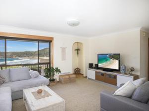 a living room with a couch and a flat screen tv at Surfside in Kioloa