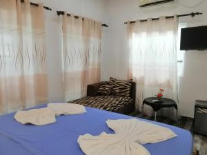 a room with a bed and a couch and curtains at Le Petit Hotel & Restaurant in Negombo