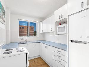 a white kitchen with white cabinets and a window at Yarramundi Unit 10 Magnus Street 47 49 in Nelson Bay