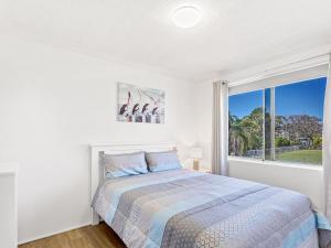 um quarto com uma cama e uma grande janela em Yarramundi Unit 10 Magnus Street 47 49 em Nelson Bay