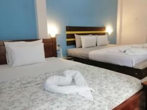 a hotel room with two beds with white sheets at Le Petit Hotel & Restaurant in Negombo