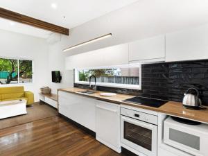 a kitchen with white cabinets and a yellow couch at Market Street, 13, The Beach House in Fingal Bay