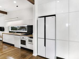 a white kitchen with white cabinets and appliances at Market Street, 13, The Beach House in Fingal Bay