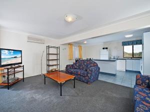 a living room with a couch and a table and a kitchen at The Breakers 16B Government Road in Shoal Bay