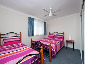 two beds in a room with pink and purple sheets at The Breakers 16B Government Road in Shoal Bay