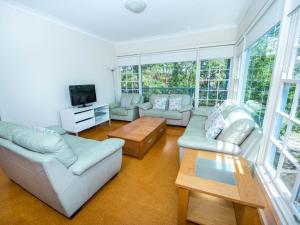 uma sala de estar com mobiliário branco e janelas grandes em Shoal Bay Avenue Unit 3 7 em Shoal Bay