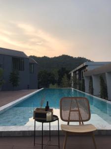 a chair and a table next to a swimming pool at Adoor hotel Khao Yai in Ban Rai