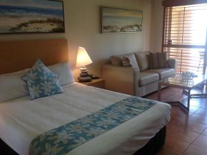 a bedroom with a large bed and a couch at at Boathaven Bay Holiday Apartments in Airlie Beach