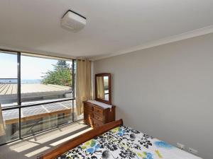a bedroom with a bed and a large window at The Crest Unit 5 6 8 Tomaree Road in Shoal Bay