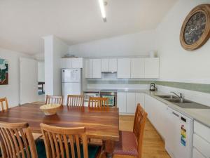 a kitchen and dining room with a wooden table and chairs at Tallwoods Beach House in Mollymook