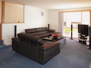 a living room with a leather couch and a television at Seaside Serenity Soldiers Point in Soldiers Point