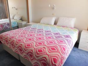 a bedroom with a large bed with a colorful bedspread at Seaside Serenity Soldiers Point in Soldiers Point