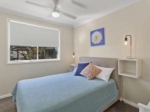 - une chambre avec un lit bleu et une fenêtre dans l'établissement Stockton Street 1 72, à Nelson Bay