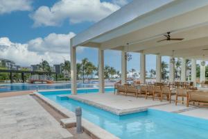 una piscina con sillas y un restaurante junto a la piscina en Hakuna Matata 725N at Mareazul Beachfront, en Playa del Carmen