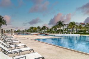 Una piscina tipo resort con tumbonas y palmeras. en Hakuna Matata 725N at Mareazul Beachfront, en Playa del Carmen