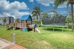 un parque infantil con juegos en un parque con palmeras en Hakuna Matata 725N at Mareazul Beachfront, en Playa del Carmen