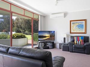 a living room with a leather couch and a flat screen tv at Fathoms 2 in Mollymook