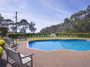 a swimming pool with two chairs and a bench at Fathoms 2 in Mollymook