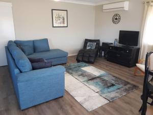 een woonkamer met een blauwe bank en een tv bij Surfair Unit 1 24 Marine Drive in Fingal Bay