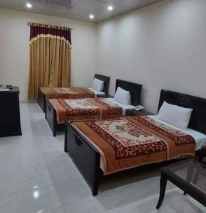 a room with three beds in a room at Decent Lodge Hotel Garden Town in Lahore