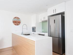 a kitchen with a stainless steel refrigerator and white walls at The Shoal Apartments, Unit 202/4-8 Bullecourt Street in Shoal Bay