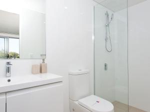 a white bathroom with a toilet and a shower at The Shoal Apartments, Unit 202/4-8 Bullecourt Street in Shoal Bay +10 photos