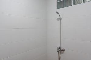 een douche in een badkamer met witte tegels bij Hotel Sukahaji Street Bandung Redpartner in Bandung