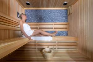 a woman is sitting in a sauna at Residence La Torre in Trieste