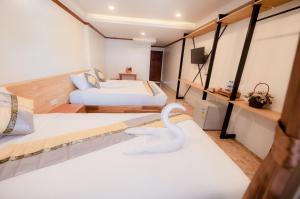 una habitación de hotel con 2 camas y un cisne en la cama en Coconut Grove Hotel Samui, en Koh Samui 