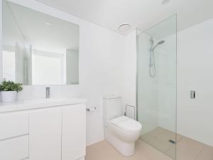 a white bathroom with a toilet and a shower at The Shoal, Unit 309/4-8 Bullecourt Street in Shoal Bay