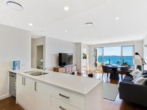 an open kitchen and living room with a view of the ocean at The Shoal, Unit 510/4-8 Bullecourt Street in Shoal Bay