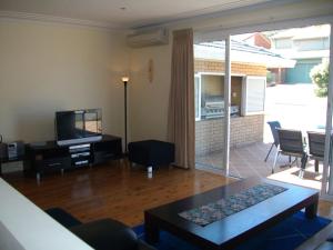 a living room with a couch and a tv and a table at Tomaree Palms 39 Tomaree Road in Shoal Bay