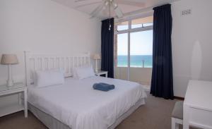 1 dormitorio con cama blanca y ventana grande en 45 Sea Lodge Umhlanga Rocks en Durban