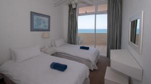 two beds in a hotel room with a view of the ocean at 45 Sea Lodge Umhlanga Rocks in Durban