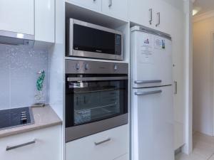 a kitchen with a microwave oven and a refrigerator at Tradewinds Unit 3 110 Victoria Parade in Nelson Bay
