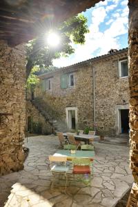 a patio with a table and chairs in front of a stone building at Les Jardins de Falguière in Saint-Jean-du-Gard