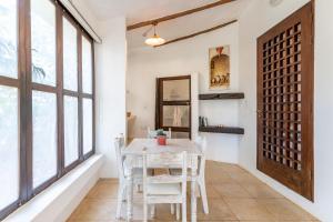 a dining room with a table and chairs and windows at Tequila Sunrise Forest Cabana - on Diani Beach in Diani Beach +13 photos