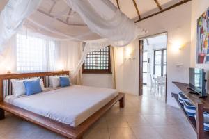 um quarto com uma cama e uma televisão em Tequila Sunrise Forest Cabana - on Diani Beach em Praia de Diani