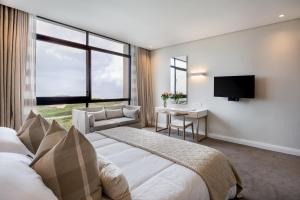 Bluewater Bay Sunrise Hotel في Amsterdamhoek: غرفة نوم بسرير ومكتب وتلفزيون