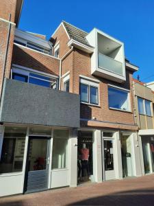 una persona parada en la ventana de un edificio en Apartment Duinvos 150m from the beach en Noordwijk aan Zee