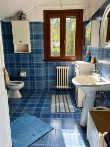a blue tiled bathroom with a sink and a toilet at Casa dei Tramonti in San Feliciano