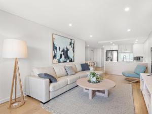 ein Wohnzimmer mit einem Sofa und einem Tisch in der Unterkunft The Shoal Apartments Unit 306 6 Bullecourt in Shoal Bay