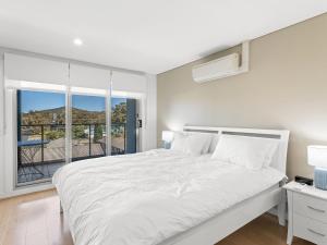 ein weißes Schlafzimmer mit einem großen Bett und einem Fenster in der Unterkunft The Shoal Apartments Unit 306 6 Bullecourt in Shoal Bay