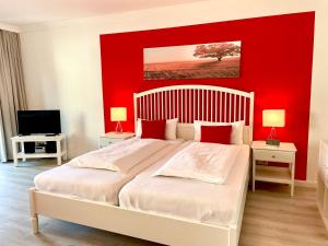 a bedroom with a large bed with a red wall at Haus Heidelerche das ThermePlus-Haus in Bad Bevensen