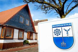 a house with a sign in front of it at Trautes Heim Ferienwohnung Sued in Maasholm +6 photos