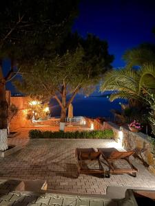 a patio with two benches and a tree at night at Beach House With Direct Access to Private Beach Near Bodrum in Çamlık