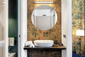 a white sink sitting under a mirror in a bathroom at Relais Antica Badia - San Maurizio 1619 in Ragusa